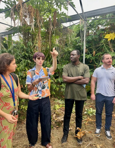 The interpreter points to a tree while speaking to people around her.